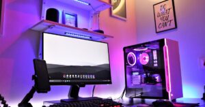A sleek gaming setup featuring RGB lighting with a desktop, monitor, and smartphone in a vibrant room.